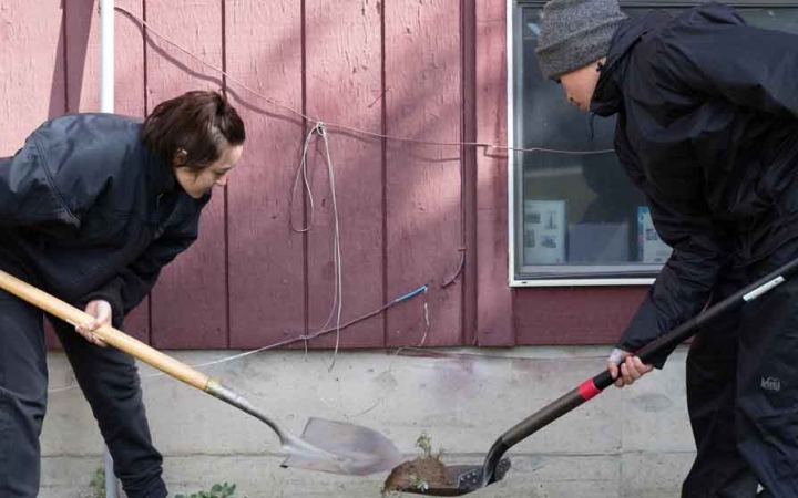 two students use shovels while doing a service project with outward bound